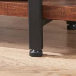 Close-up of a black metal furniture leg with an adjustable leveling foot, attached to a Bookshelf and resting on a wooden floor.