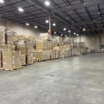 Stacks of palletized boxes for Inventory Management 2 ODM/OEM orders are plastic-wrapped and neatly organized along the spacious warehouse walls with high ceilings and concrete floors.
