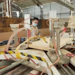 A worker wearing a mask operates Wooden furniture 9, a large OEM woodworking machine, in an industrial factory setting.