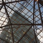 Experience the innovative design of abcdhe, as shown by a tall office building framed through a striking geometric glass and metal ceiling, set against a partly cloudy sky. OEM or ODM solutions available.