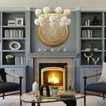 A modern living room with gray Toptrue built-in shelves, a round coffee table, two armchairs, and a lit fireplace beneath a large decorative wall piece.