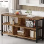 The 01.01.C-1_结果 sofa table, made of wood and metal with open shelves for books, baskets, a plant, and fruit bowl, is placed against the window behind the sofa.