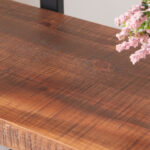 A close-up of a rustic wooden tabletop with natural grain, partially decorated with pink flowers—ideal for showcasing the 04.03 Solid Wood Bookcase, 2-Tier Industrial Rustic Vintage Etagere Bookshelf in Distressed Brown.