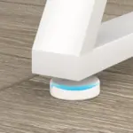 Close-up of a white furniture leg on 07.01.C_结果, a round white floor protector with blue accent, set on wood flooring. Perfect for ODM and OEM projects needing stylish, practical flooring solutions.