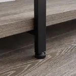 Close-up of the BC02-01 06 - 03 2-Shelf Rustic Industrial Bookshelf's black metal leg with adjustable leveling foot on a wood-textured floor beside a wooden shelf; ideal for OEM or ODM furniture solutions.