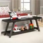 The Industrial Wood Bench, Black Oak, sits at the foot of a bed with festive bedding and is styled with holiday decorations and gifts in a bright bedroom.