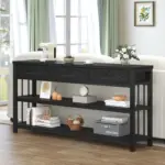 The Sofa Table with 3 Drawers in Black Oak, adorned with books, baskets, a flower vase, a mixer, and ornaments on its two shelves, stands in a bright living room.