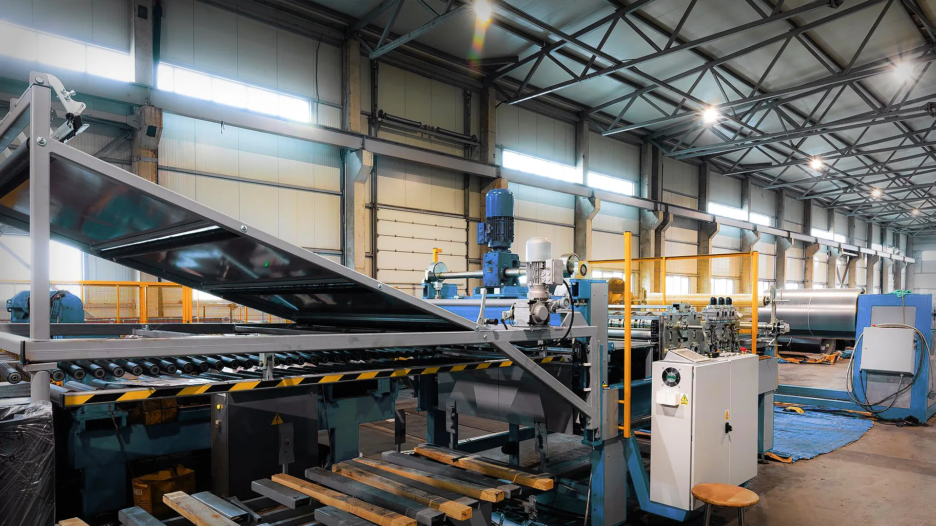Industrial factory interior with Toptrue conveyor belts, machinery, control panels, and equipment beneath a high metal ceiling with bright overhead lights. Wooden pallets are in the foreground.