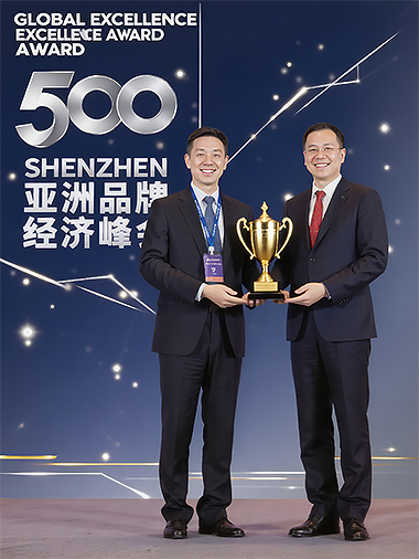 Two men in suits stand smiling on stage, holding a gold trophy together. The backdrop displays "500 Shenzhen Global Excellence Award” in English and Chinese, highlighting Toptrue’s outstanding achievement.